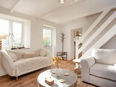 a living room with two couches and a table at Harlequin Cottage in St Austell