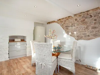 a kitchen and dining room with a table and chairs at Harlequin Cottage in St Austell