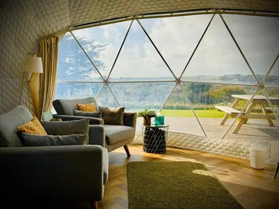 a living room with a large glass window at Sunset Ridge - Luxury Geodesic Dome set in the beautiful countryside in Porkellis