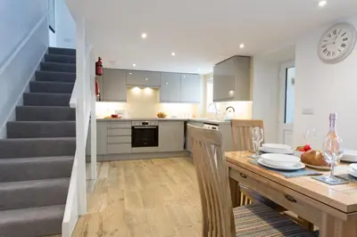 a kitchen and dining room with a table and a staircase at Cornish Views in Camborne