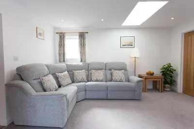 a living room with a gray couch and a window at Cornish Views in Camborne