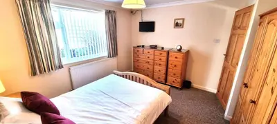 a bedroom with a bed and a dresser and a window at Trenare in Perranporth