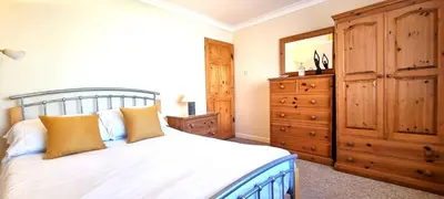 a bedroom with a bed and a wooden dresser at Trenare in Perranporth