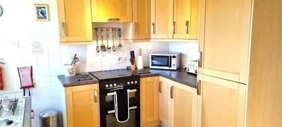 a kitchen with wooden cabinets and a stove and a microwave at Trenare in Perranporth