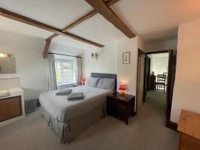 a bedroom with a bed and a table and a window at Lilac Cottage Tintagel in Tintagel