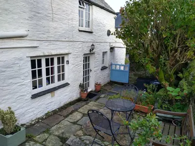 a patio with a table and chairs in front of a house at Lilac Cottage Tintagel in Tintagel
