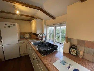 a kitchen with a sink and a refrigerator at Lilac Cottage Tintagel in Tintagel