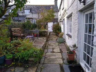 a small garden with a table and chairs in front of a house at Lilac Cottage Tintagel in Tintagel