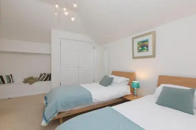 a bedroom with two beds and a chandelier at Polmoor in St Ives