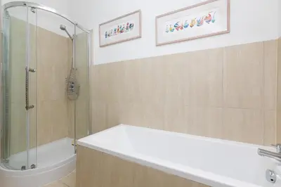a bathroom with a shower and a tub and a sink at Polmoor in St Ives