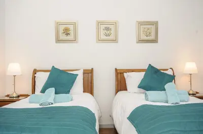 a bedroom with two beds with blue pillows at Lambley View in Bude