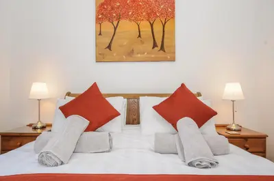 a bedroom with a bed with red and orange pillows at Lambley View in Bude