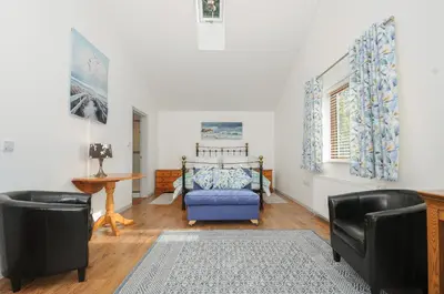 a living room with a bed and two chairs at Lambley View in Bude