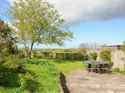 a patio with a table and chairs in a yard at Lambley View in Bude
