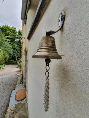 a bell hanging on the side of a building at Primrose Cottage in Helston