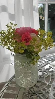 a white vase filled with flowers on a table at Primrose Cottage in Helston