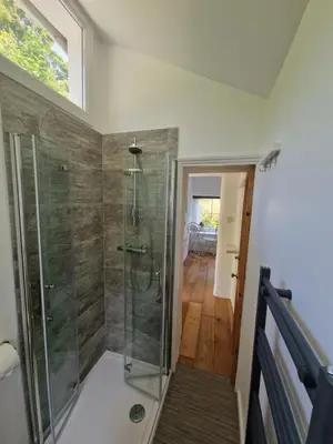 a bathroom with a shower with a glass shower stall at Primrose Cottage in Helston