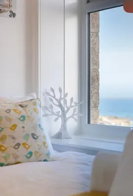 a bed with a pillow in front of a window at Sea Salt sea views parking in St Ives