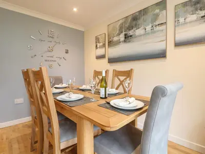 a dining room table with chairs and a clock on the wall at Manuka in Falmouth
