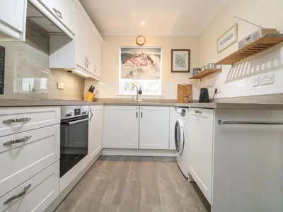 a kitchen with white cabinets and a sink at Manuka in Falmouth