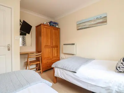 a bedroom with two beds and a cabinet and a chair at Manuka in Falmouth