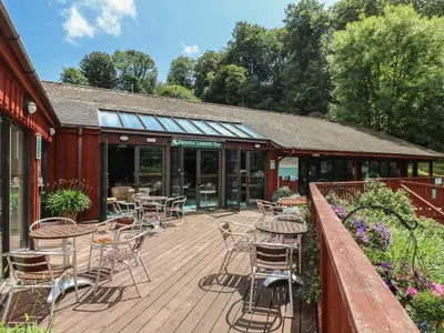 a wooden deck with chairs and tables on a building at Manuka in Falmouth