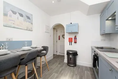 a kitchen with blue cabinets and a table with chairs at Rame in Looe