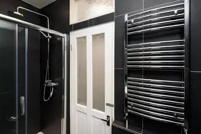 a black bathroom with a shower and a glass door at Rame in Looe