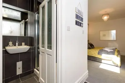 a bathroom with a sink and a bed in a room at Rame in Looe