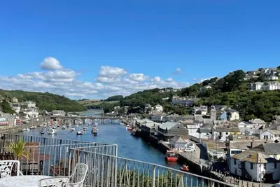 a group of boats docked in a river with houses at Rame in Looe