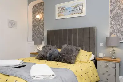 a bedroom with a bed with yellow sheets and gray pillows at Rame in Looe