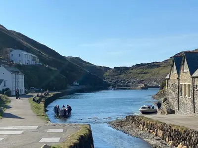 a group of people on horses crossing a river at Harbour Light in Boscastle