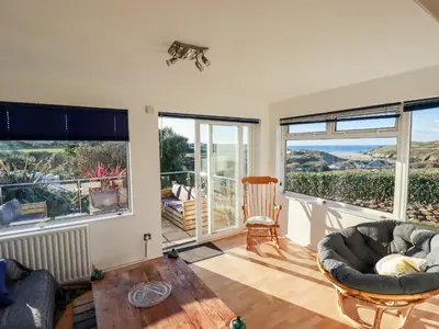 a living room with a couch and chairs and windows at Seacroft in Newquay