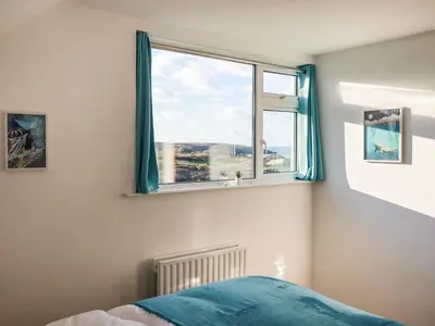 a bedroom with a window with blue curtains at Seacroft in Newquay