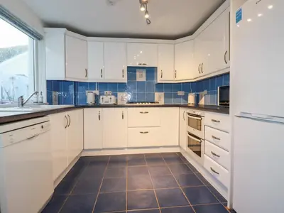 a kitchen with white cabinets and a tile floor at Seacroft in Newquay