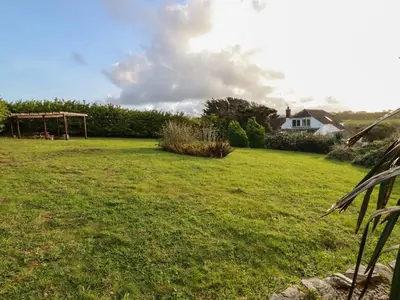 a field of grass with a house in the background at Seacroft in Newquay
