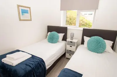 two beds in a room with two blue pillows at Pet Friendly Sea view Villa Millendreath Looe in Looe