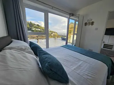 a bedroom with a bed with a large window at Pet Friendly Sea view Villa Millendreath Looe in Looe