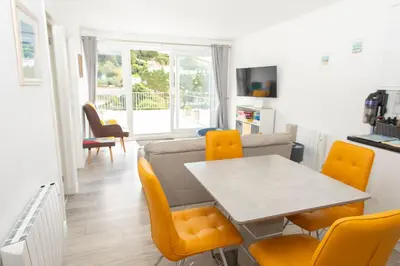 a living room with a table and yellow chairs at Pet Friendly Sea view Villa Millendreath Looe in Looe