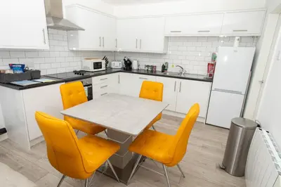 a kitchen with a table and yellow chairs at Pet Friendly Sea view Villa Millendreath Looe in Looe