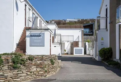 a street with white buildings and a stone wall at 3 Europa Court in Mawgan Porth in Mawgan Porth