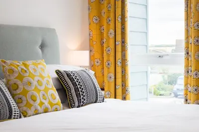 a bed with yellow and white pillows and a window at 41 Tre Lowen in Fistral, Newquay in Newquay