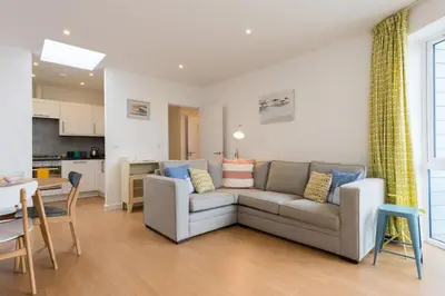 a living room with a couch and a kitchen at 41 Tre Lowen in Fistral, Newquay in Newquay