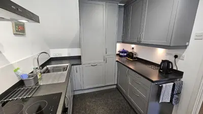 a kitchen with white cabinets and a black counter top at Corner Cottage in Saint Mawes