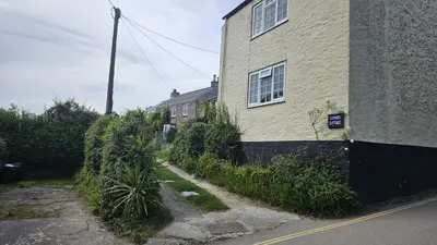 a house with a sidewalk next to a building at Corner Cottage in Saint Mawes