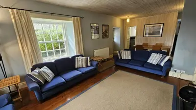 a living room with blue couches and a table at Corner Cottage in Saint Mawes