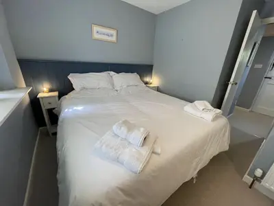 a bedroom with a white bed with two towels on it at Crugsillick Court in Veryan