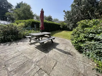 a picnic table with a red umbrella on a patio at Crugsillick Court in Veryan