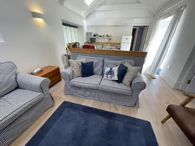 a living room with two couches and a kitchen at Crugsillick Studio in Veryan