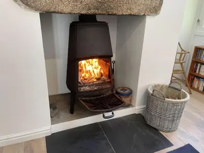a fireplace in a living room with a fire in it at Crugsillick Studio in Veryan